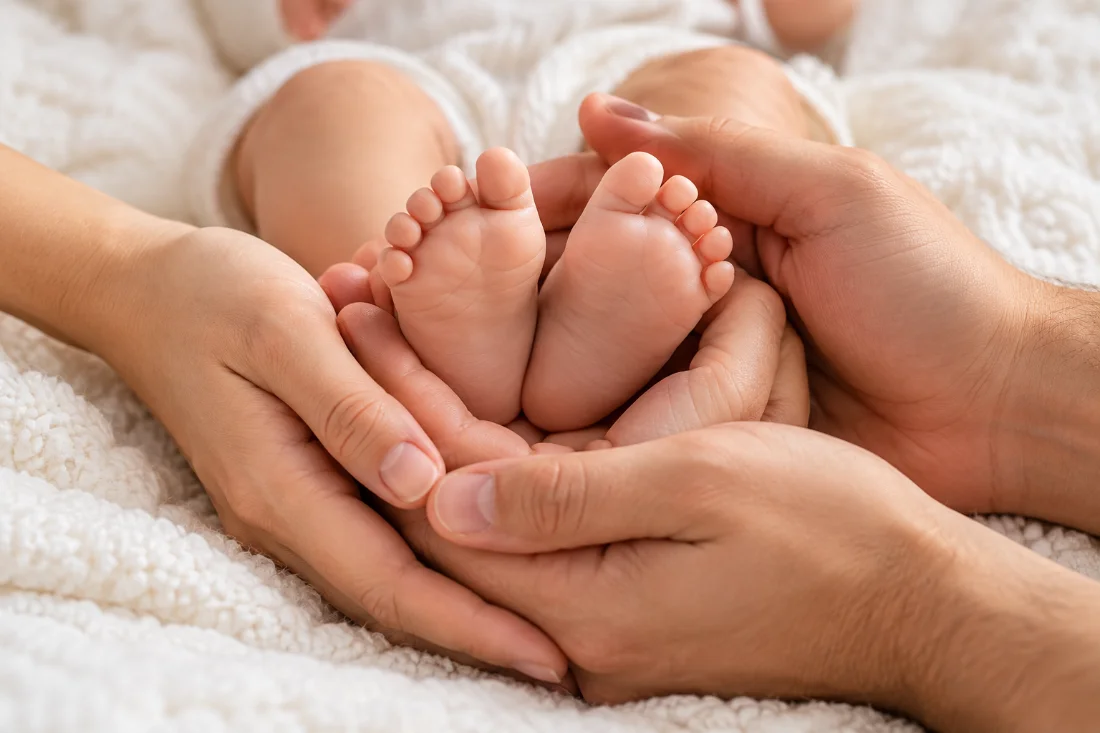 Piecitos de bebé en manos de los padres